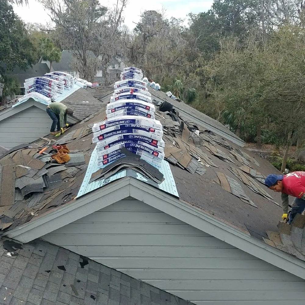 A group of people working on the roof of a house.