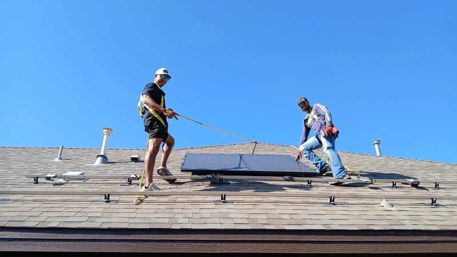 Two men working on a roof with solar panels.