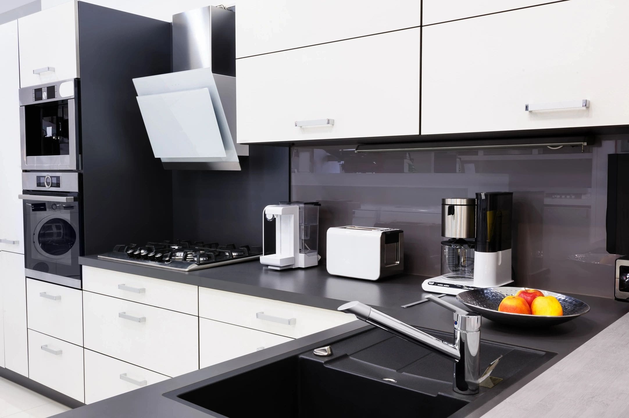 A kitchen with black and white cabinets, sink and counter.